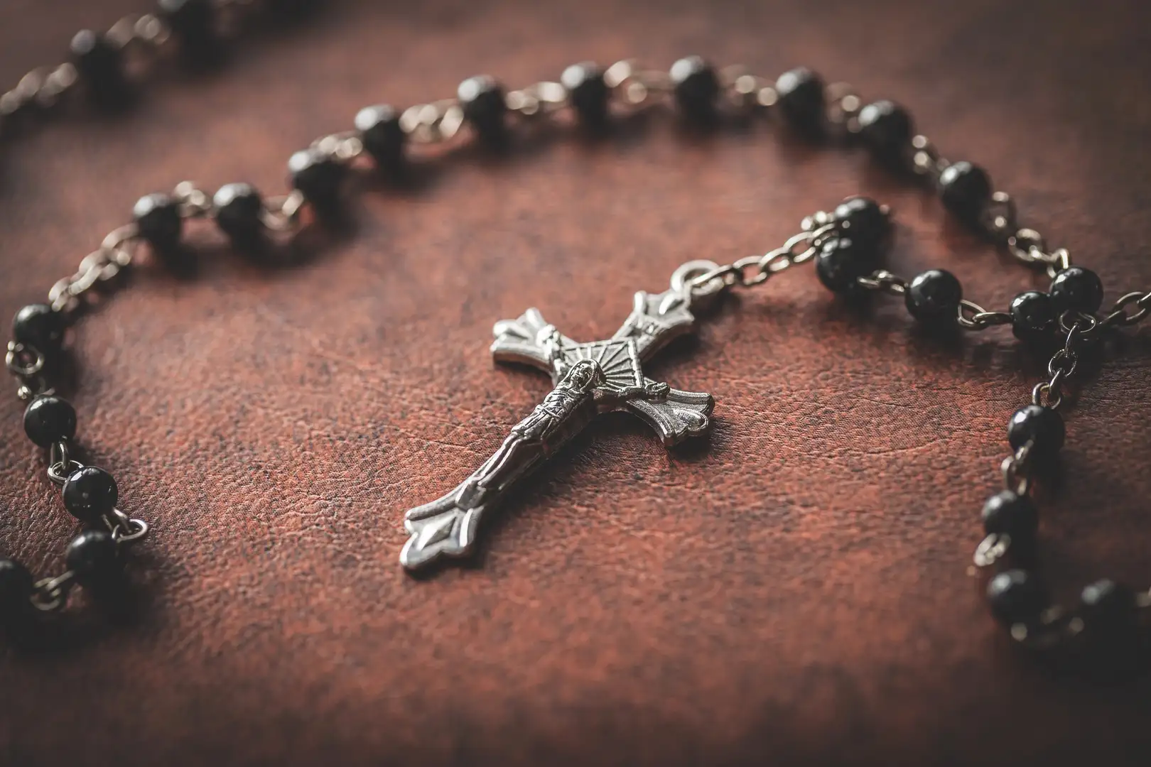 A rosary sits on leather.